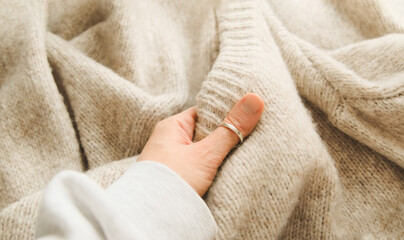 Hand touching knitted wool cloth or warm fluffy sweater. Handcraft knitting woolen fabric surface.  - obrazy, fototapety, plakaty