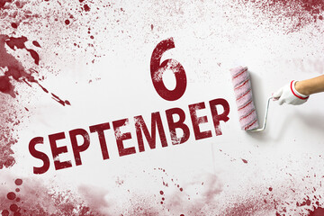 September 6th. Day 6 of month, Calendar date. The hand holds a roller with red paint and writes a calendar date on a white background. Autumn month, day of the year concept.