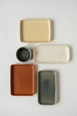 Neutral colour handmade ceramics, empty craft ceramic plates and bowls on white background. Flat lay, top view