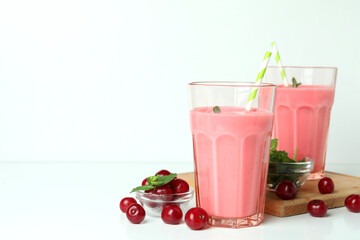 Glasses of cherry smoothie and ingredients on white table