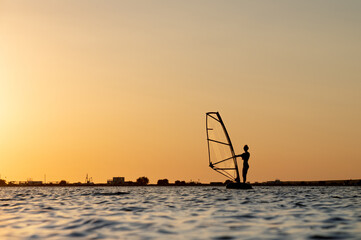 Silhouette of a young woman kitesurfer at sunset. Trainings in calm weather on the estuary