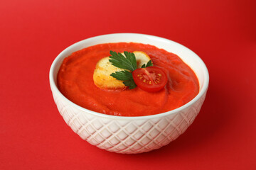 Bowl of tasty Gazpacho soup on red background