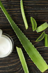 Aloe vera leaves, slices and cream on wooden background