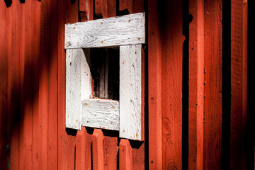Rote Hausfassade aus Holz. Weiß gerahmtes Fenster. Schwedisches Haus. Hintergrund. Red wooden house facade. White framed window. Swedish house. Background.
