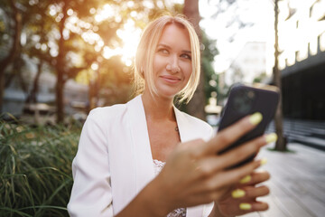 Beautiful young blonde businesswoman using smartphone in the city