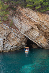 Fototapeta premium Tourist boat sailing at sea near the cave