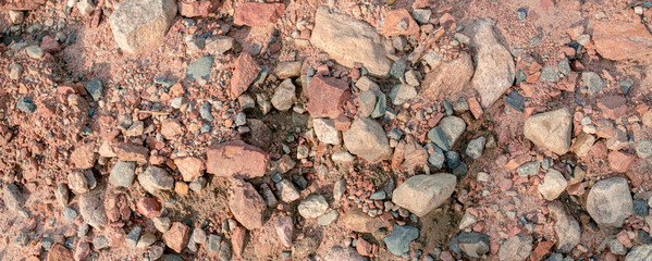 Banner Lots of natural stone with red and gray tints and sand. Stone background.