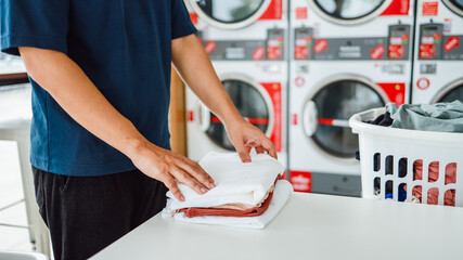 Man doing launder holding basket with dirty laundry of the washing machine in the public store. laundry clothes concept