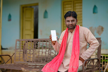 technology concept : Young indian farmer showing smartphone at his home