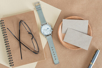Flat lay watch with accessories objects and business cards on modern rustic brown paper at home...