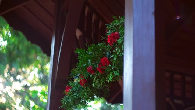 Wedding Decoration Garland made of Fake Plastic Red Roses and Leaves Hanging above Entrance to Wooden Bower in Public City Park