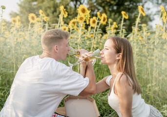 Obraz premium Young couple having picnic on sunflower field at sunset