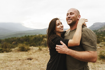 Happy couple in love hugging smiling and having fun in the mountains