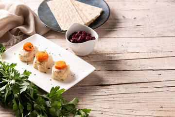 Traditional Jewish gefilte fish with beetroot and matzah bread on wooden table.Copy space