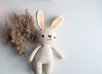 Crocheted white bunny with dry ears on a white background.
