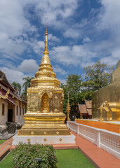 Naklejka premium Beautiful view of small golden stupa with Buddha statue in niche at famous landmark Wat Phra Singh buddhist temple, Chiang Mai, Thailand
