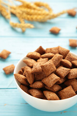 Bowl with chocolate pads on blue wooden background. Vertical photo