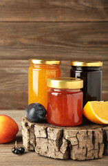 Assortment of jams, seasonal fresh berries and fruits on grey background.