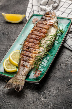 Baked trout fish with salt, lemon on black background. Healthy eating concept. vertical image. top view. place for text