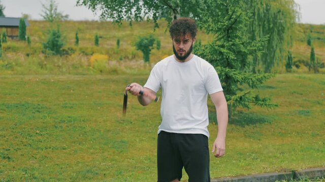 man twists nunchucks in nature