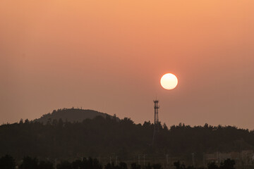 Fototapeta premium The setting sun is above the telecommunication signal tower on the mountain