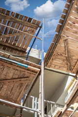 Fototapeta premium Scaffolding and scaffolding with wooden decks, against a blue sky. Performing construction work at height. Construction safety.