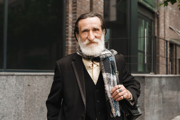 White senior man in scarf looking at camera outdoors