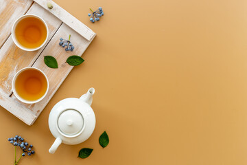 Ceramic white teapot and black tea in two cups, top view