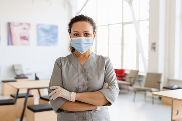 Middle eastern cleaning woman in face mask looking at camera