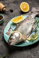 Fresh rainbow trout with salt, pepper, lemon and rosemay. Tasty fishes preparing for lunch. Healthy eating concept. vertical image. top view. place for text