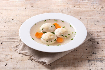 Traditional Jewish matzah ball soup on wooden table