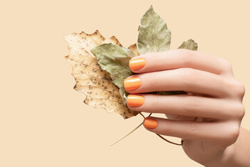 Female hand with orange nail design. Glitter orange nail polish autumn manicure. Woman hand hold...