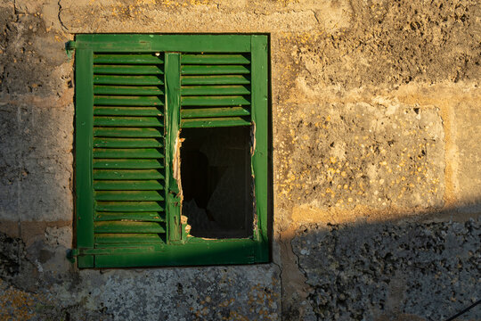 Close-up of a green Mallorcan shutter on a rustic house broken by vandalism and squatters