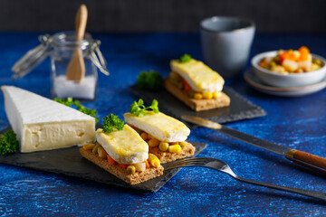 Toast with vegetables and grilled cheese. Toast with vegetables and French cheese gratin. Top view.