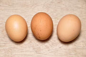 Three chicken eggs on a wooden table