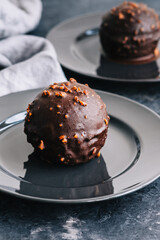 Chocolate dessert with cream, nuts and biscuit on plate.
