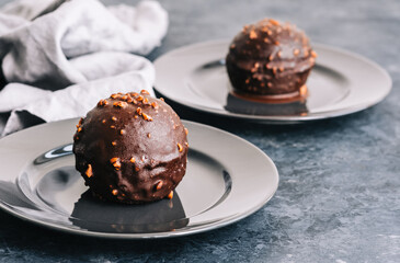 Chocolate dessert with cream, nuts and biscuit on plate.