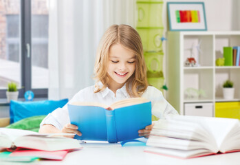 Fototapeta na wymiar education and school concept - happy smiling student girl reading book over home background