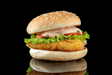 Burger with chicken cutlet, salad and mayonnaise. On a black mirrored background.