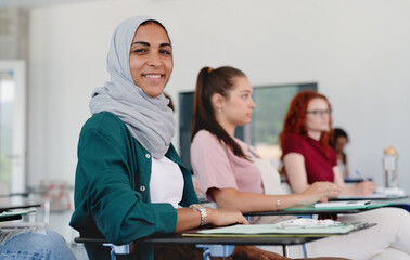Portrait of islamic university student sitting in classroom indoors, looking at camera.
