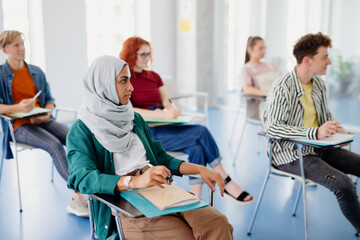 Obraz premium Portrait of multiethnic group of university students sitting in classroom indoors, studying.