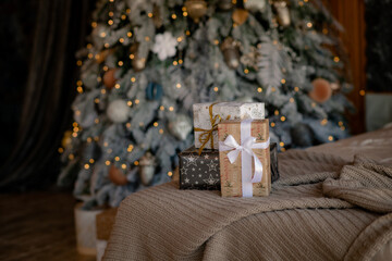 Beautiful Christmas gift boxes on the bed near the Christmas tree bokeh lights in the room. Christmas background with copy space and place for text. Christmas discount time