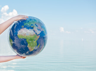Inflatable ball in the hands of a child on the background of the sea
