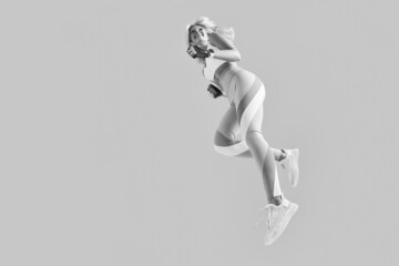 Sportswoman feeling happy, jumping and stretching. Black and white concept of sport and sportswear