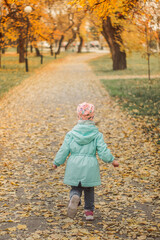 a girl runs along the road in autumn through the leaves