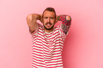 Young caucasian man with tattoos isolated on pink background  screaming with rage.