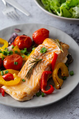 Baked red fish fillet Arctic char on a plate with vegetables, mix salad in a bowl, delicious hearty healthy dinner
