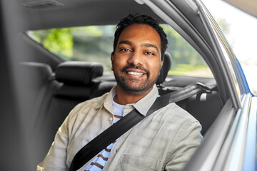 transportation, vehicle and people concept - smiling indian male passenger in taxi car