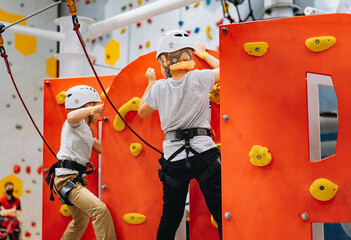 caucasian boys of 7-8 years old climbing in adventure park passing obstacle course. high rope park indoors