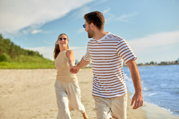 summer holidays, leisure and people concept - happy couple running along beach